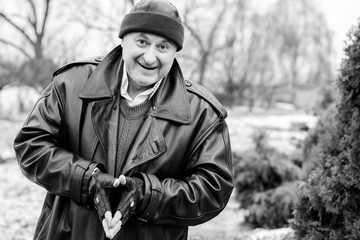 American Mature Happy Man Smiling with good mood at nature outside. Portrait of happy elderly man against winter forest background on a travelling 