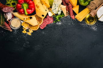 A bottle of wine, cheeses and traditional sausages on a wooden background. Brie cheese, blue cheese, gorgonzola, fuete, salami. Free space for text. Top view.