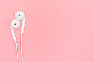 Top view Lovely Closeup of White Earphones on Pink Pastel plastic texture background. Pastel color concept, Minimal concept. Copy space. Music is my life concept. Valentine concept