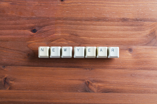 Happy new year word on computer keyboard keys buttons on wooden background