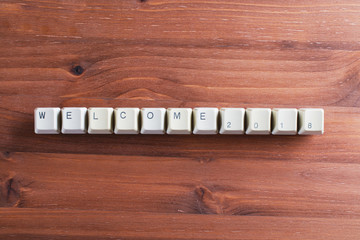 Welcome 2018 new year on computer keyboard keys buttons on wooden background