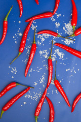 Hot chili pepper and sea salt on blue background. Top view.