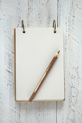 Notebook Mockup. mockup with  notepad  and wooden brown  pen on a white shabby background. Blank empty notepad.  top view, copy space.