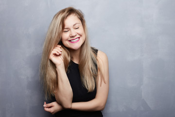 Close up portrait of happy Caucasian female with appealing appearance looks with smile, has long blond hairstyle, glad to be photographed, expresses positive emotions. People, health and joy concept.