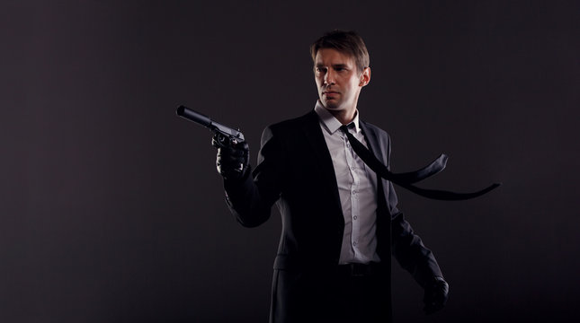 Image of man with developing tie in leather gloves with gun