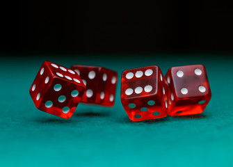 Picture of several red dice falling on green table on black background