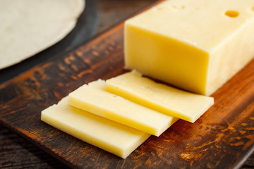 pieces of cheese on a clay plate on a wooden table.