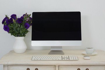 Desktop pc, vase and coffee on table