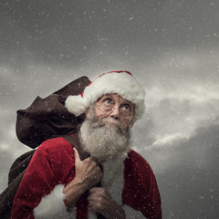 Santa Claus carrying Christmas gifts - obrazy, fototapety, plakaty