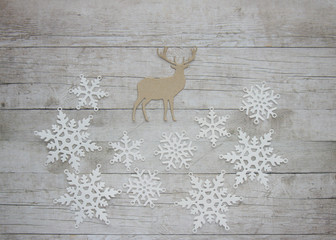 White paper snowflakes and a deer on wooden background, christmas and new year, scandinavian design	