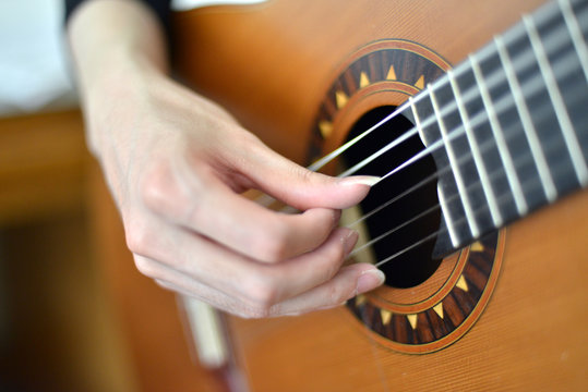 Female hand playing on electric guitar close up.