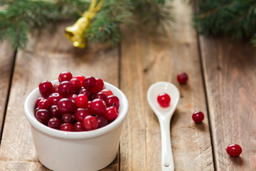 A small bowl of cranberries with sugar on a wooden table with  a white spoon © ozhukovaphoto