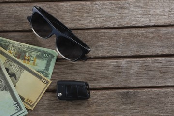 Sunglasses and currency note on wooden plank