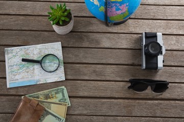 Currency notes and travelling accessories on wooden plank