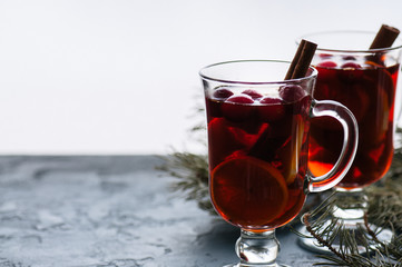 Mulled wine. Christmas hot drink with citrus, apple and spices in a glass cup on a black background.