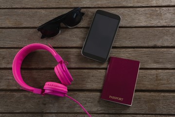 Headphones, sunglasses, passport and mobile phone wooden plank