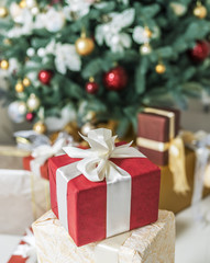 Fototapeta na wymiar Red gift box and decorated New Year Tree on the background.