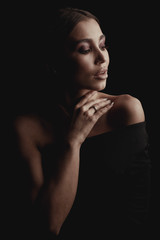Dark studio portrait of amazing elegant woman in black dress.
