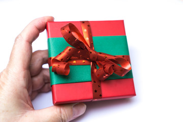 Ein hübsch verpacktes Geschenk in der Hand gehalten, weißer Hintergrund