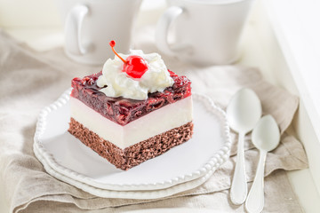 Obraz na płótnie Canvas Delicious jelly cherry cake on white plate with cream
