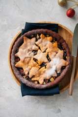 Chocolate gingerbread crust mince pie with vanilla stars on a white stone background