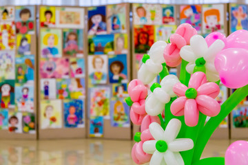 Competition of children's drawings. Exhibition of children's art. Colorful balloons in the foreground. Defocused background.