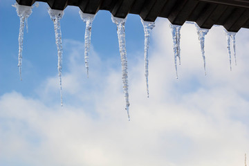 Icicles hanging on roof at winter. Natural ice formation of ice crystals hanging on roof edge at winter