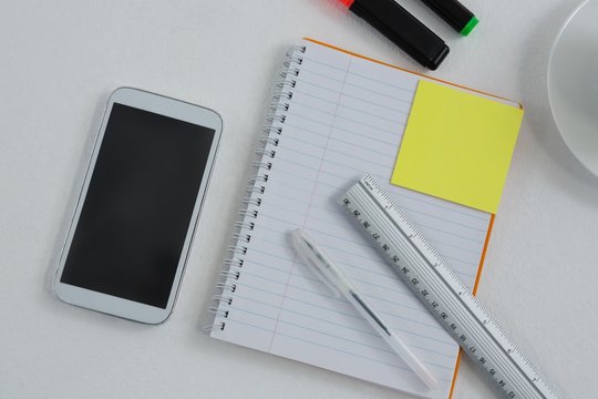 Mobile phone and stationery on white background