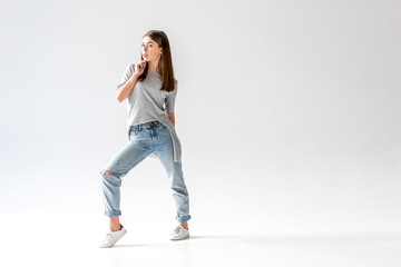 young stylish woman in jeans and grey shirt looking at camera,  isolated on white
