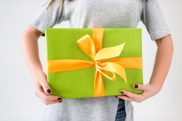 partial view of woman holding wrapped present in hands isolated on grey