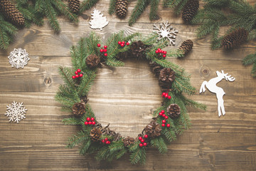 Christmas wreath of spruce branches with holly berries on wooden board. Flat lay. Top view.