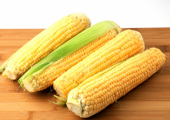 Corn cob on wooden plank isolated on white