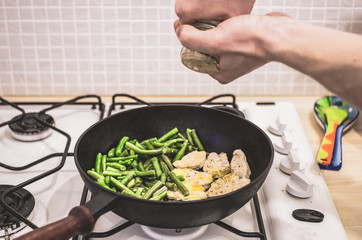 Green beans with chicken stewed on a cast-iron frying pan