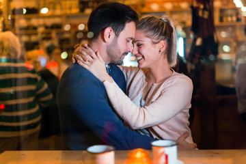 Happy couple hugging at bar and having date