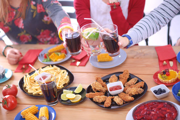 Top view of group of people having dinner together while sitting at wooden table. Food on the table. People eat fast food.