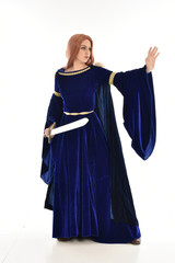  full length portrait of girl wearing long blue velvet gown and fur lined cloak, standing pose  on white background.