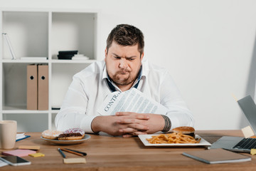 confused overweight businessman choosing donuts or hamburger with french fries