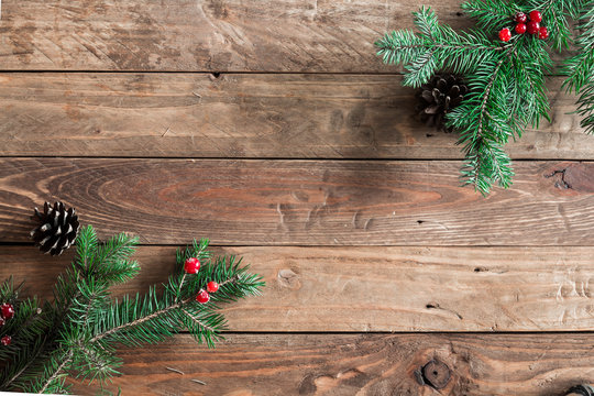 
A wooden background with sprigs of fir cones and cranberries. Christmas background.