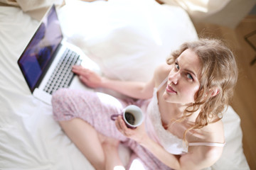 Young beautiful woman sitting in bed with laptop.