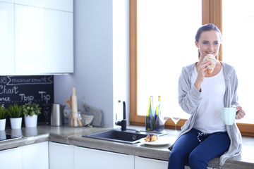 Beautiful young woman using a digital tablet in the kitchen.