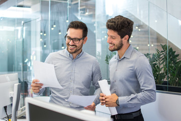 Smiling business men in formal wear discussing contract in the office. 