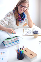 Young woman sitting at a desk among books. Student