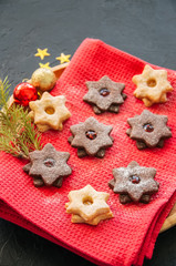 Plate of chocolate and vanilla linzer star cookies with raspberry and orange jam. Festive Christmas dessert.