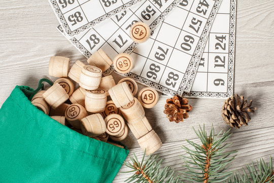 Wooden lotto barrels with bag and game cards for a game in lotto, Christmas fir tree branches and cones