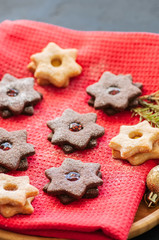 Fototapeta na wymiar Plate of chocolate and vanilla linzer star cookies with raspberry and orange jam. Festive Christmas dessert.
