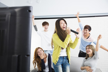 young woman holding microphone and singing at karaoke. - obrazy, fototapety, plakaty