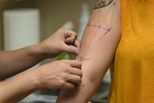 Professional tattoo artist makes a tattoo on a womans hand