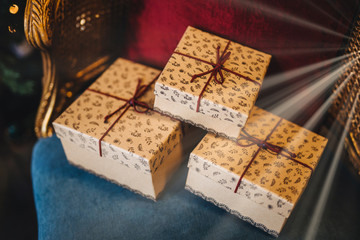 Wrapped gift boxes lie on armchair. Prepared surrpise on birthday or some other holiday. Horizontal picture of three present boxes with ribbons. Celebration and holiday concept.