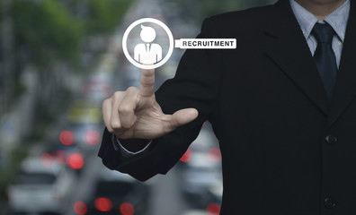 Hand pressing businessman with magnifying glass icon over blur of rush hour with cars and road, Business recruitment concept