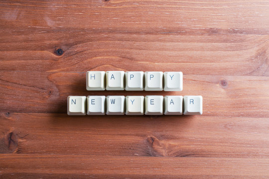 Happy new year card concept on computer keyboard keys on a wooden background